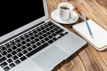 Workspace setup with laptop coffee and notepad on wooden...