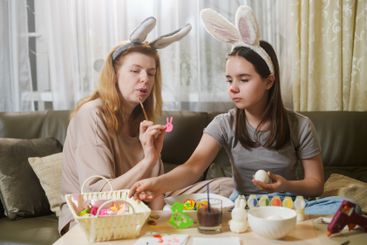 Mother And Daughter Preparing Easter Egg Decorations.