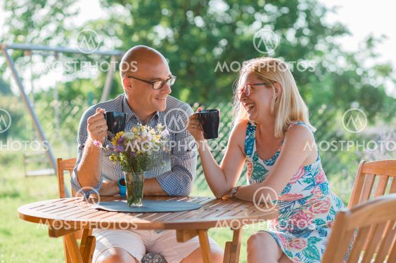 Young couple drinking coffee in the backyard in the morning