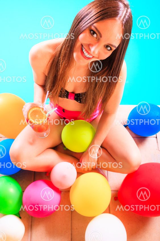 Happy woman with balloons and cocktail at poolside