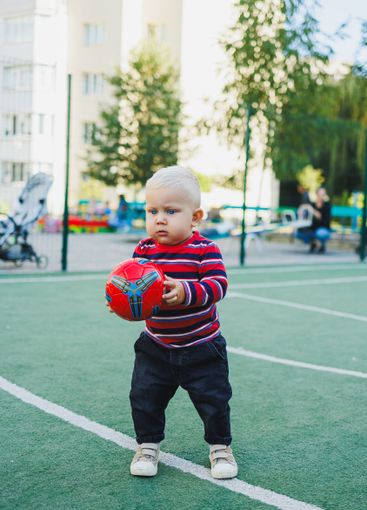 A fair-haired one-year-old boy in jeans and sneakers...