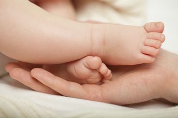 Parent holding in the hands feet of newborn baby