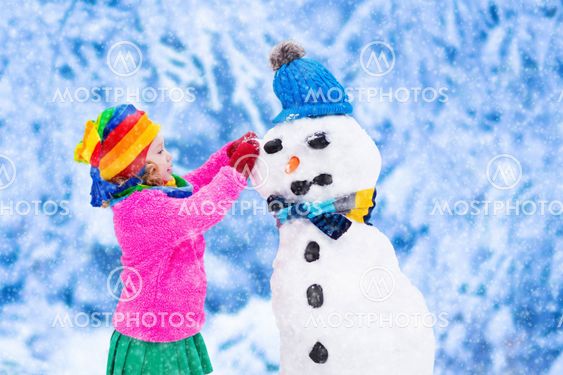 Little girl building a snow man in winter