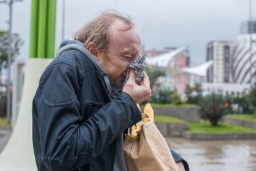 Adult man sneezes into a tissue. Seasonal allergy, cold...