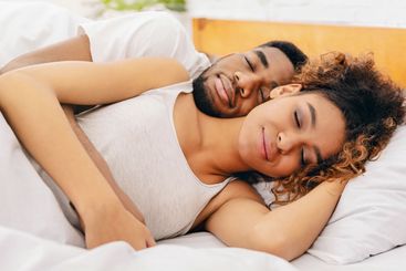 Couple cuddling peacefully in their sleep in bed