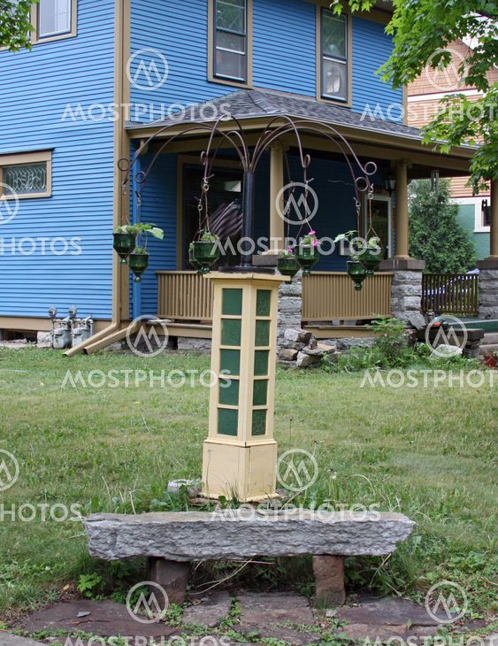 plant holder and bench in front of a blue house
