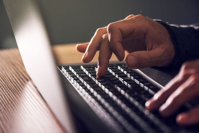 Computer programmer and hacker hands typing laptop keyboard
