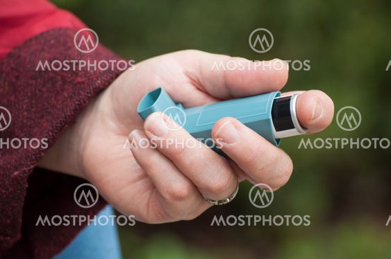 asthma aerosol in hand of woman in outdoor