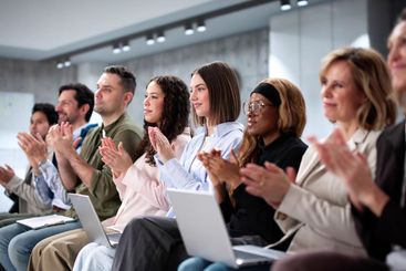 Thrilled crowd at business event watching diverse...