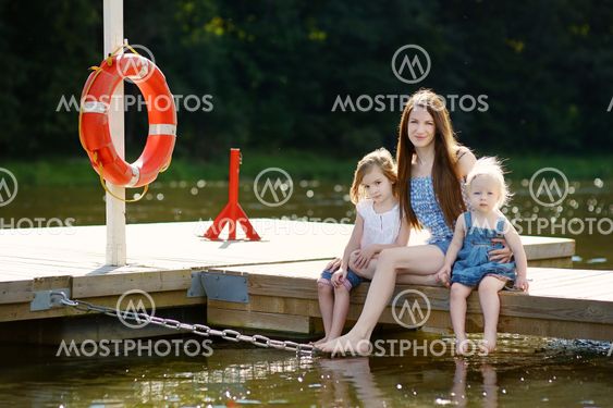 Mother and her children sitting on a wooden pier