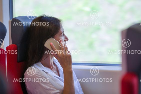 Young businesswoman talking on the phone traveling by train