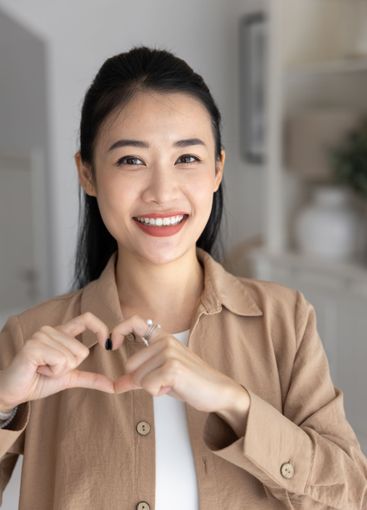 Cheerful beautiful young Asian woman showing finger...