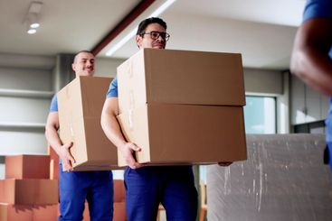 Diverse Residential Movers Packing Boxes in Living Room...