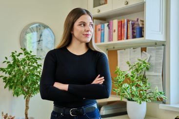 Confident young woman with crossed arms in home interior