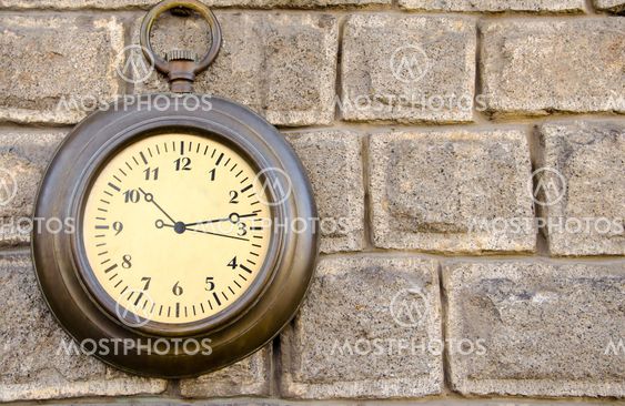 Old street clock on a stone wall