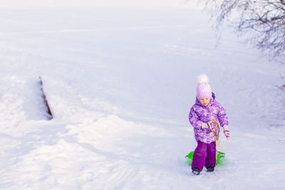 Little girl pulls a sled in warm winter day
