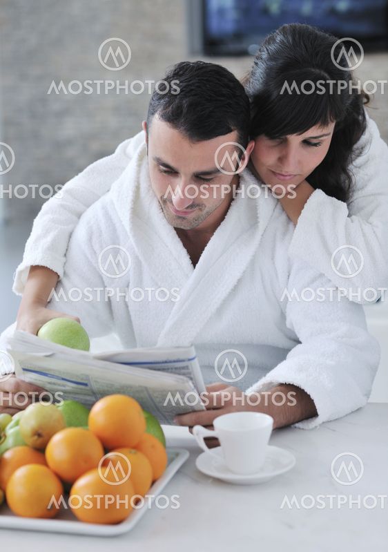 Happy couple reading the newspaper in the kitchen at breakfast