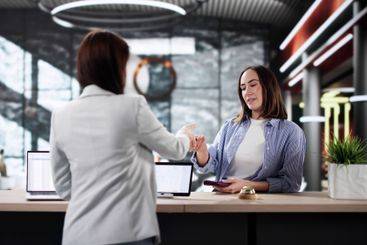Hotel receptionist greets woman checking in