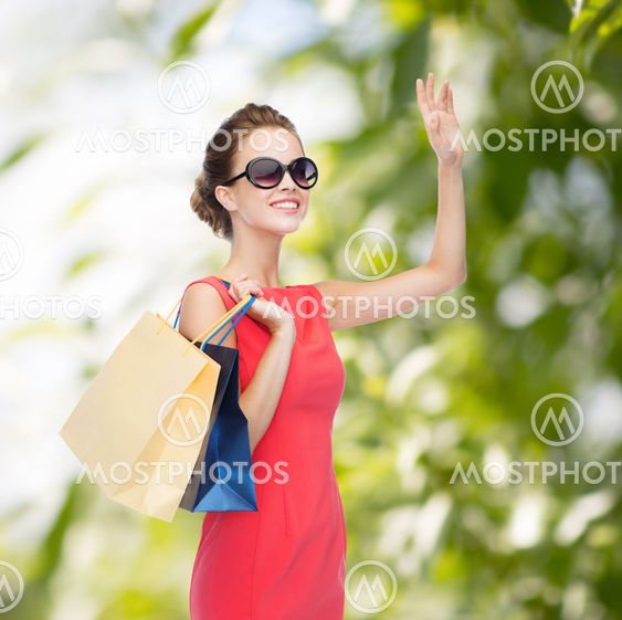 smiling elegant woman in dress with shopping bags