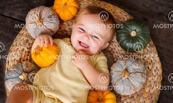 happy baby on the basket with different pumpkins