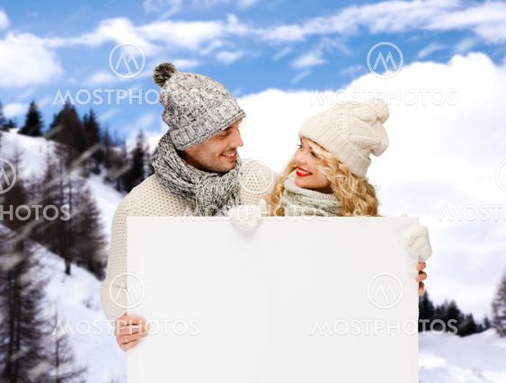 smiling couple in winter clothes with white board