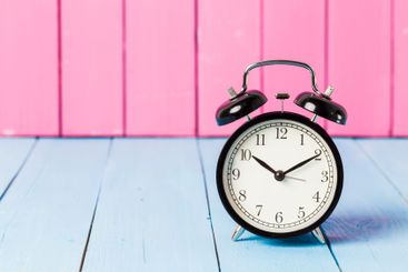 Black vintage alarm clock on wooden table