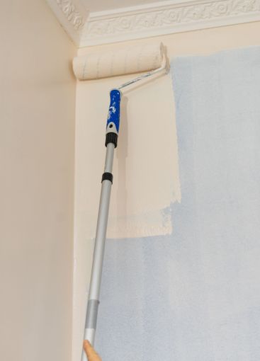 Person applying paint on wall