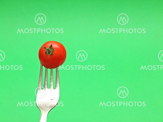 fresh tomato on fork with green background