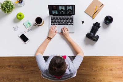 woman with camera working on laptop at table
