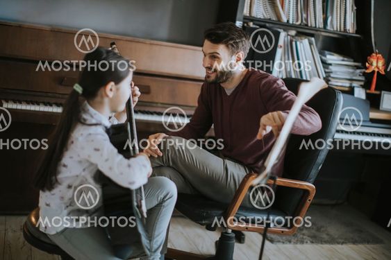 Little girl playing guitar with her music teacher in the...