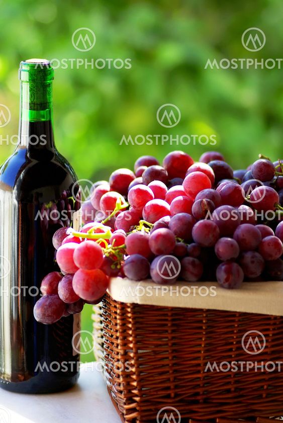 bottle of red wine and grapes in basket