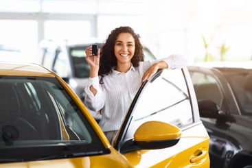 Attractive brunette woman holding key, buying new car,...