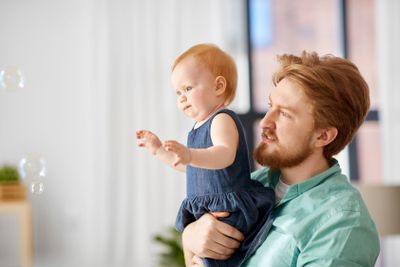 father and baby daughter with soap bubbles at home