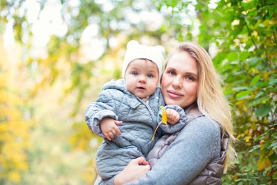 Mother and her little daughter play cuddling on autumn...