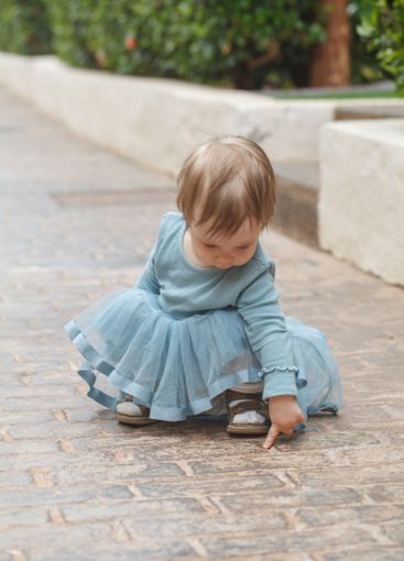 Playful baby girl 1 year old playing in the yard outdoors