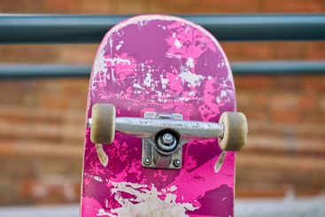 Used pink skateboard against stone wall in urban setting