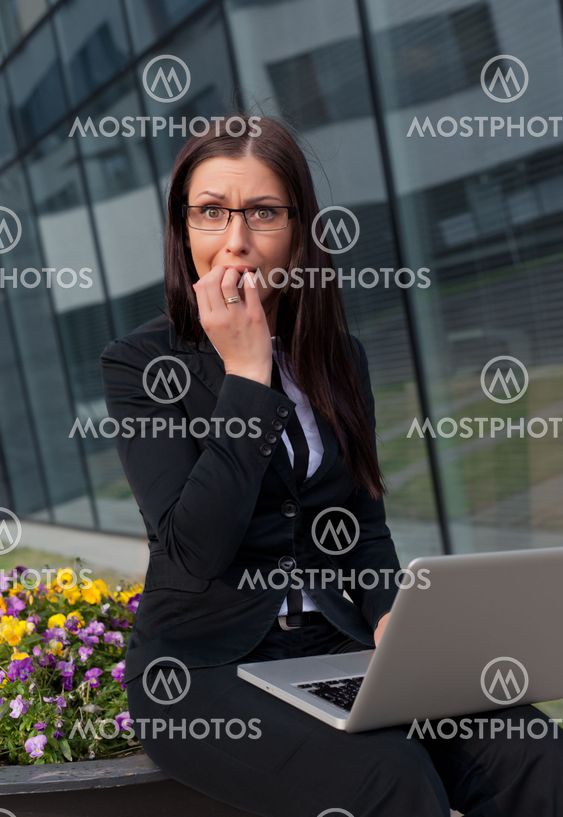 Frightened and stressed beautiful business woman biting her fingers