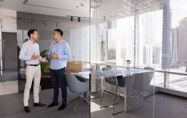 Two diverse businessmen standing and talking in office...