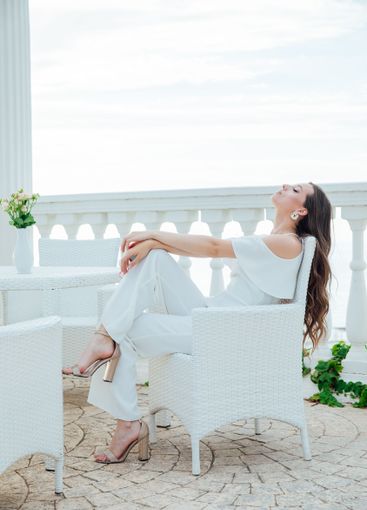 fashionable brunette woman in white suit sitting at...