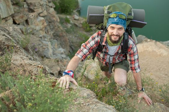 Young caucasian man with backpack climbing the rock