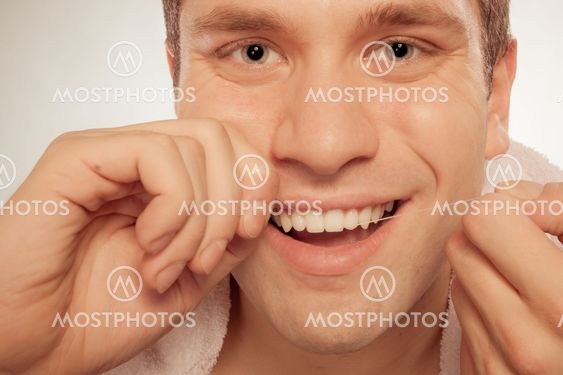 Young man cleaning her white teeth with dental floss