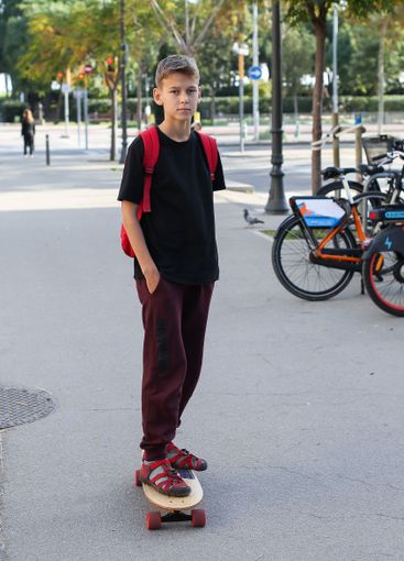 Handsome teenager standing with skateboard. Adolescent...