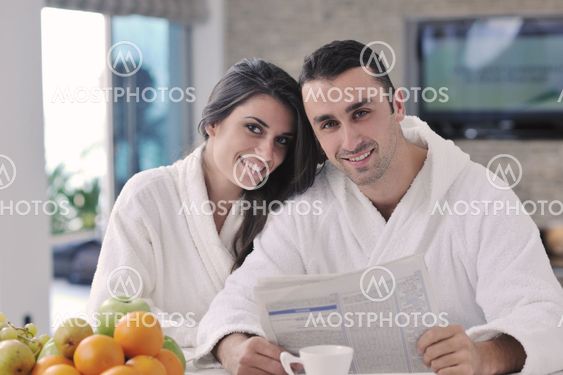 Happy couple reading the newspaper in the kitchen at breakfast