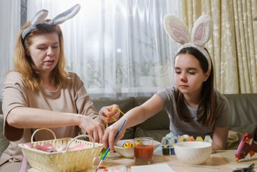 Mother And Daughter Decorating Easter Eggs At Home.