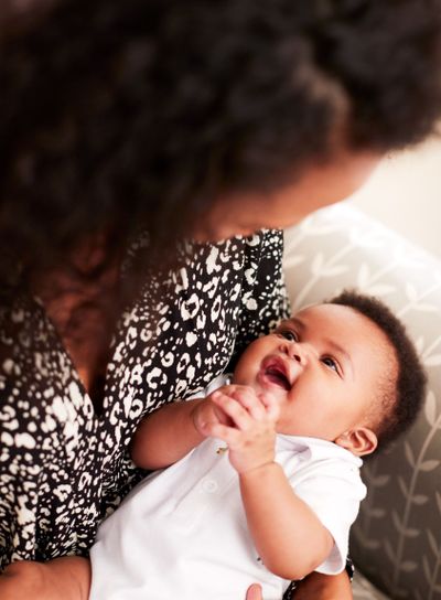 Loving Mother Sitting In Chair Cuddling Baby Son In...