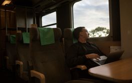 Man with laptop sitting on train