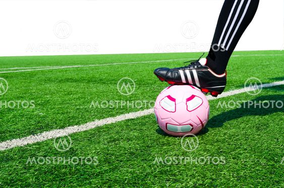 Ball with his feet on the football field in sunny day