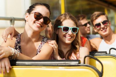 group of smiling friends traveling by tour bus