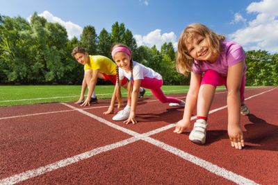 Three smiling children in ready position to run