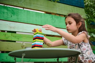 Young girl concentrating while building a colorful tower...